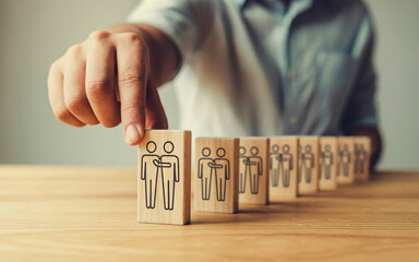 Hand setting up wooden blocks with teamwork icons representing collaboration and partnership for business strategy and success in a corporate environment on a table