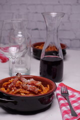 Tavola apparecchiata per due con piatti di coccio con bucatini all'amatriciana, piatto tipico italiano