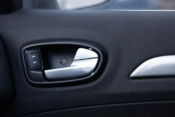 Car door handle with power window controls showing interior design and modern features in a vehicle