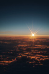 Golden-hour sunrise above sculpted atmospheric cloud layers, warm inner glow contrasting with cool blue shadows, intense central starburst flare