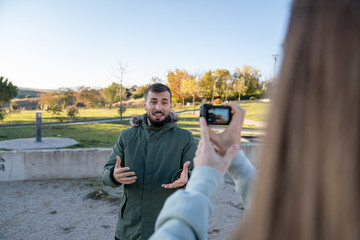 Man vlogging outdoors while a long-haired man films with an action camera, creating content for a social media channel.