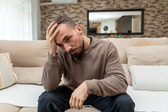 Man experiencing severe anxiety and depression while sitting on sofa, coping with mental health problems and stress