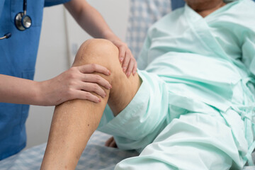 Obraz premium Doctor checking Asian elderly woman patient with scar knee replacement surgery in hospital.
