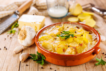 homemade gratin potatoes in ceramic dishware with ingredients