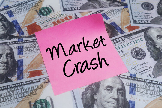 A clear message of Market Crash on a pink sticky note atop scattered hundred-dollar bills, illustrating a severe economic downturn and financial instability
