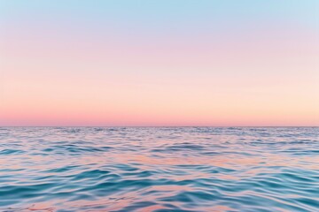 Obraz premium The scene captures a calm ocean at dusk, where soft waves gently ripple beneath a pastel sky. The horizon is serene, blending hues of pink and blue as night approaches