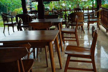 set of brown wooden tables and chairs on the shaded outdoor cafe terrace.
