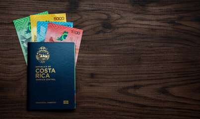 Costa Rican passport with colón banknotes on wood, symbolizing travel and economy.