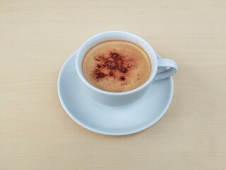Cappuccino coffee in white cup with wooden table background. High angle view 