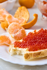 Sandwich with red caviar and tangerines. Traditional Russian treat on the New Year's table.
