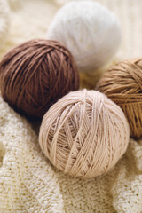 Balls of knitting yarns in natural colors on white knitted background, knitting, crocheting supplies.