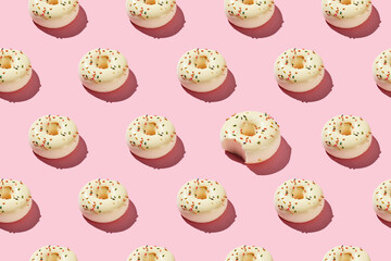 Bitten Donut Pattern on Pink Background. Sweet Treats with Sprinkles in Minimalist Flat Lay Style.