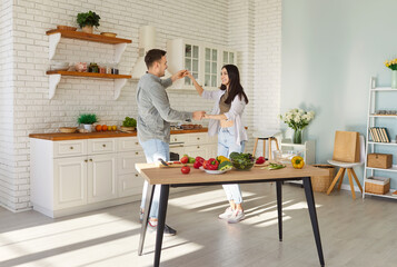 Happy couple at cozy modern kitchen home, healthy eating habits, enjoy cooking in modern place, culinary hobby, new flat owners family celebrate relocation day housewarming dancing to feel happy