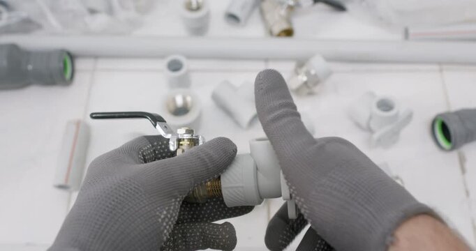 Plumber threads polypropylene coupling onto brass valve by hand. Worker aligns pitch and tightens connection applying ptfe tape before testing seal for quality assurance