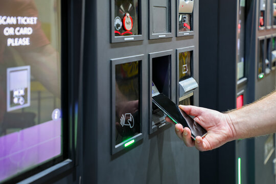 Smart payment at a modern self-service terminal: a customer taps a smartphone on the illuminated reader to complete a digital transaction. Sleek design highlights the ease of contactless tech.