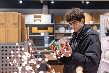 Teenager Choosing Christmas Ornaments in Store – Holiday Shopping, Festive Retail and Gen Z Consumer Behavior. Christmas Balls in Festive Store