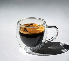 Rich Espresso Coffee in Double-Walled Glass Mug on Minimalist Grey Background with Shadows