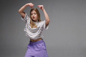 Young caucasian female teen dancing in striped shirt and purple pants