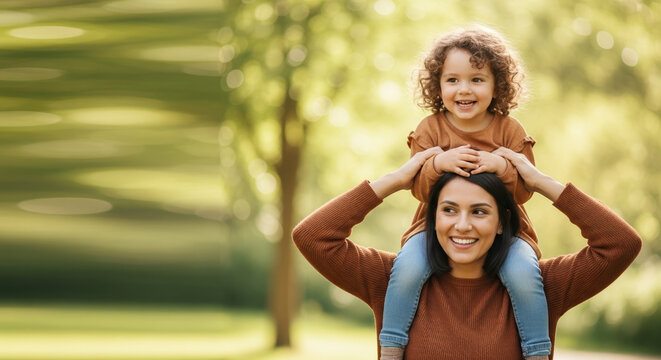 Celebrating Adoption Month with happy family, mother and daughter. Enjoying Adoption Month, cheerful mom carries her little girl on shoulders in sunny park, symbolizing love and togetherness.