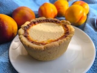 freshly baked bun with sour cream filling on a white plate surrounded by ripe nectarines.
