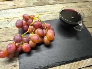 Beautiful juicy pink grapes on a cutting board, next to a cup of freshly squeezed juice