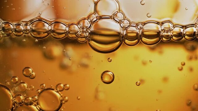 Golden liquid with rising bubbles for science or food background in macro view.