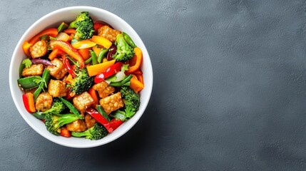 Stir fry with colorful vegetables and tempeh in white ceramic bowl, plantbased eating, Asianinspired dish