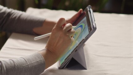 Close-up, artist drawing peacock feather on tablet screen while sitting at table - Powered by Adobe