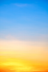 Sunset or sunrise sky with a vibrant gradient of orange, gold, and soft blue. Clear atmosphere with wispy clouds. Peaceful, natural light background. hope, freedom, new day Concepts, Vertical