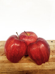 Close-Up of Three Ripe Red Gala Apples with Stems, White and Wood Background, Clean