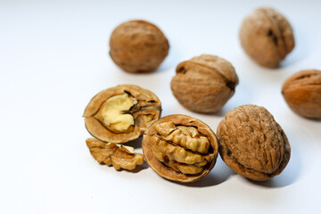 Whole and peeled brown walnuts on the white background