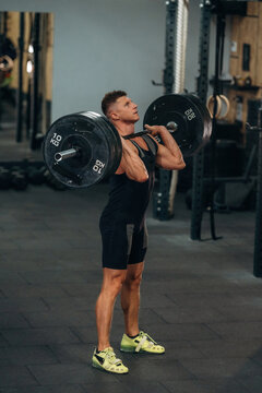 Demonstrating the proper technique. Athletic man performing weightlifting exercises with a barbell in a gym
