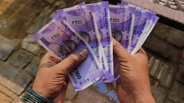 An indian woman counting 100 rupees indian currency notes.