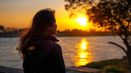 Fototapeta premium Back view silhouette with blurred form framing sharp cinematic sunset over western river with golden glow, with copy space