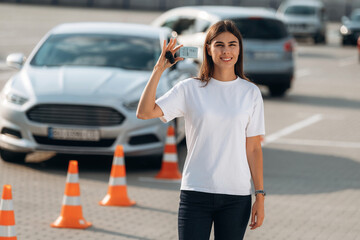 Passed the exam. Happy woman is holding her driving license, driving school test passed