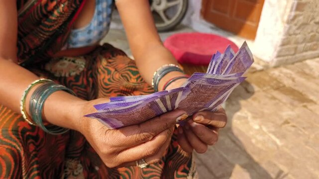 An indian woman counting 100 rupees indian currency notes.
