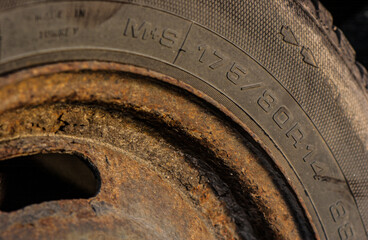 Close macro of rusty steel car wheel and tire texture.