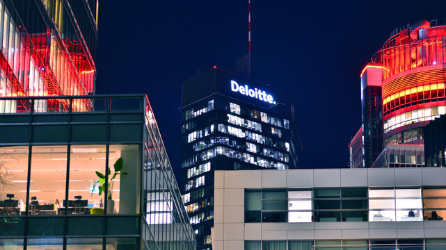 Warsaw, Poland. 20 November 2025. City life after dark. Dense corporate development in center city in the night. Lights street and buildings towering around them. The sign of the company Deloitte.