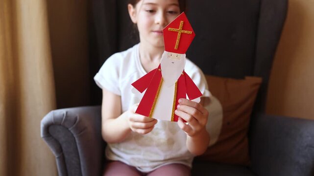 paper craft for kids. child plays with DIY toy Saint Nicholas for sinterklaas day. ball-jointed doll waves its arms