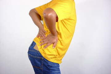 Lower back pain, close-up of a young man experiencing lower back pain after working at home. An adult man holding his lower back, chronic back pain, bone calcification, osteoporosis.Healthcare concept
