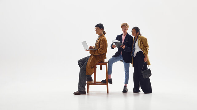 Modern creative professionals in stylish outfits collaborating and smiling with positive energy. Concept of fashion teamwork, startup culture, expression of individuality and optimism.