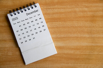 Top view of December 2025 calendar on wooden table. Year end concept.