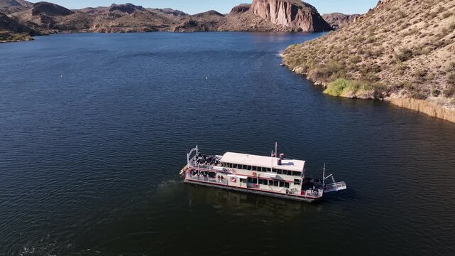 Aerial view of a boat sailing on a lake surrounded by desert mountains under a clear blue sky, Apache Junction, Arizona, United States.