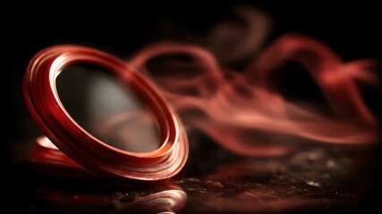 A vibrant red, circular object is the focus against a black background. Shadows enhance the design