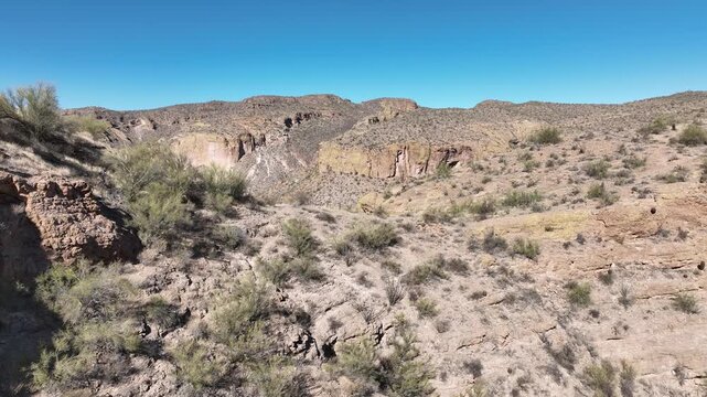 Aerial view of arid, rocky terrain, the landscape is painted in earthy tones under a clear, expansive sky, Apache Junction, Arizona, United States.