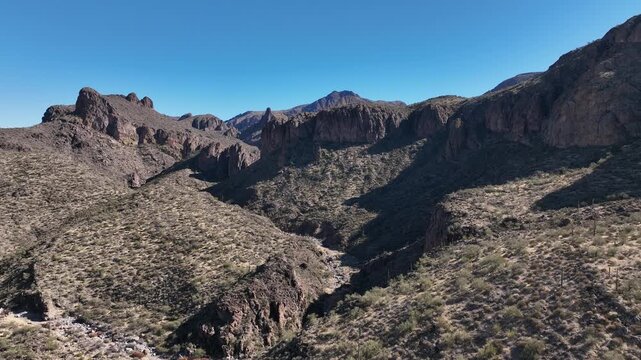 Aerial view of rugged mountains and arid desert landscape with contrasting shadows creating a dramatic scene, Apache Junction, Arizona, United States.