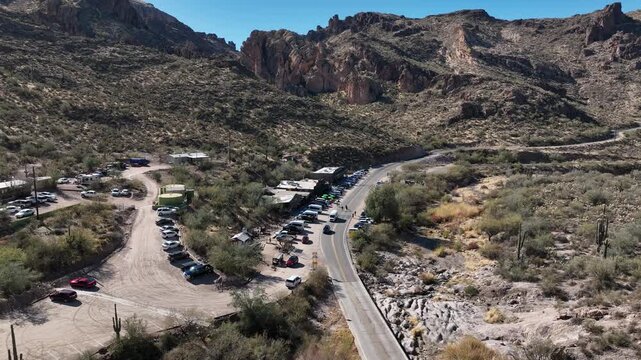 Aerial view of a road with cars parked on both sides, leading towards a mountainous landscape, showcasing Arizona's natural beauty, Apache Junction, Arizona, United States.