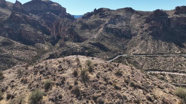 Aerial view of rugged mountains, sparse vegetation, and a winding road cutting through the landscape, showcasing nature's harsh beauty, Apache Junction, Arizona, United States.