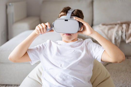 A teen boy engaging in virtual reality gaming experience at home - Powered by Adobe