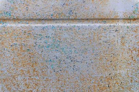 A fragment of an old gray metal wall with cracked paint. A stiffening rib is present. Background. Texture.